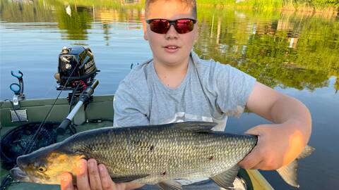 Ein junger Angler mit dem vom Boot im Lipno-See gefangenen Rapfen